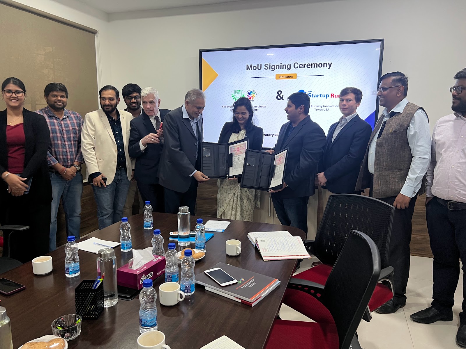 Mission group in a program setting with an MoU signing ceremony display