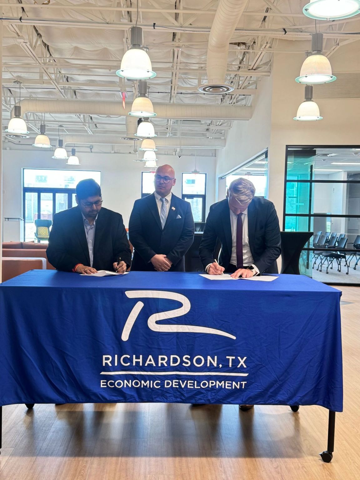Two representatives sign documents at a Richardson Economic Development table